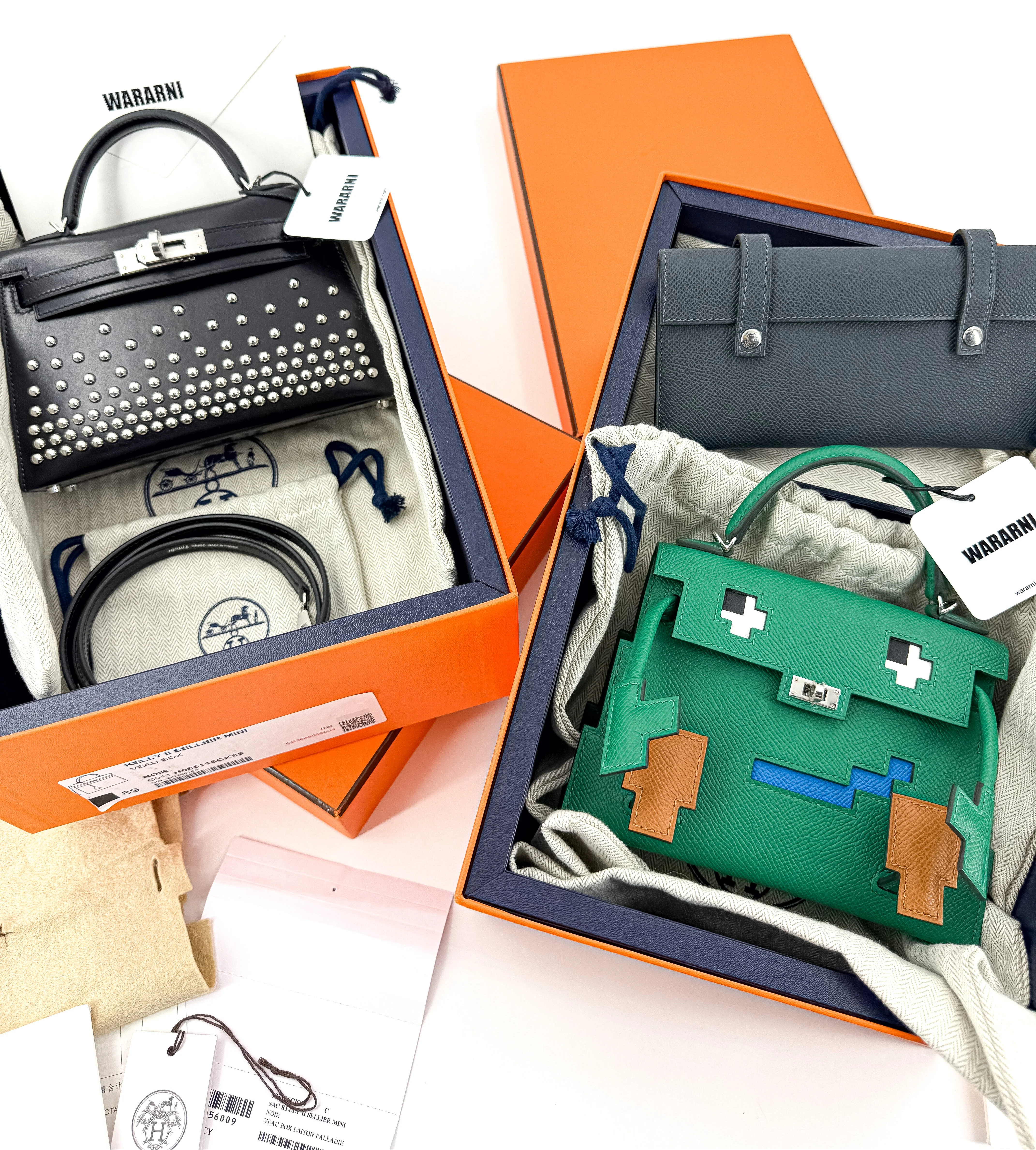 Three handbags in open boxes with visible brand labels on a white background, an hermes black mini kelly studd and a green hermes kelly doll picto